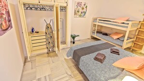 Un dormitorio con armario, literas y una pequeña mesa con tabla de planchar.