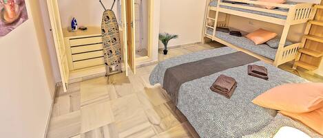 A bedroom with a wardrobe, a bunk bed, and a small table with an ironing board.