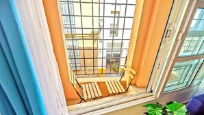 Una habitación con ventana que da a un patio, una banca de madera y una planta en maceta.