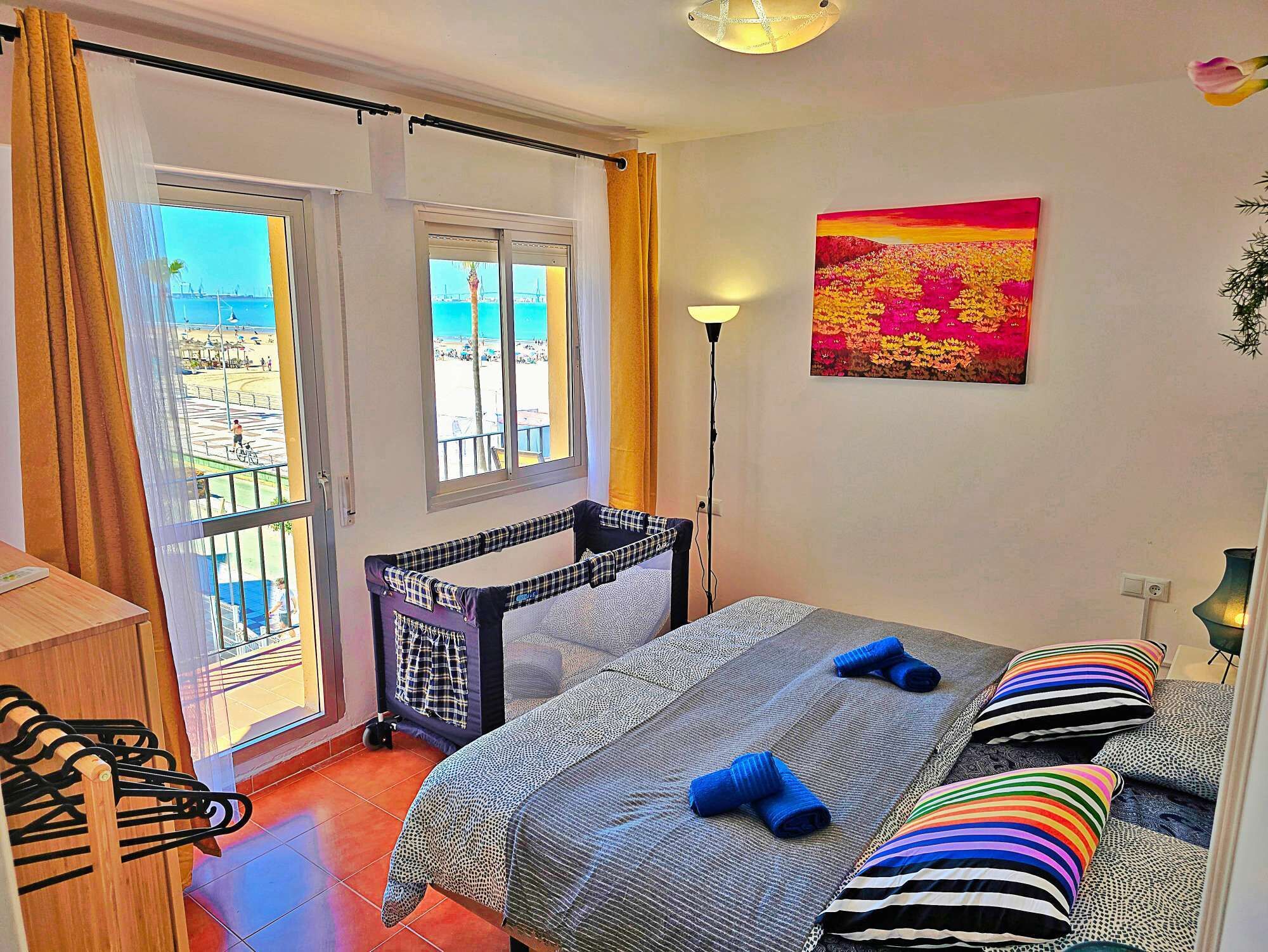 Une chambre à coucher avec un lit, une fenêtre avec des rideaux, un tableau et une lampe.