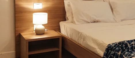 A neatly made bed with white linens and a wooden headboard.