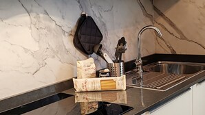 A kitchen with a marble backsplash, a stainless steel sink, and a utensil holder with pasta boxes and a grater. - Brand new renovated apartment "The Dormouse" 10 minutes from the historic center (Firenze)