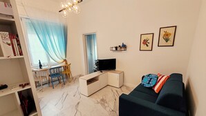 A living room with a sofa, a TV, a dining area with chairs, a bookshelf, and a chandelier. - Brand new renovated apartment "The Dormouse" 10 minutes from the historic center (Firenze)