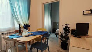A dining area with a table, chairs, a potted plant, a television, and a window with curtains. - Brand new renovated apartment "The Dormouse" 10 minutes from the historic center (Firenze)