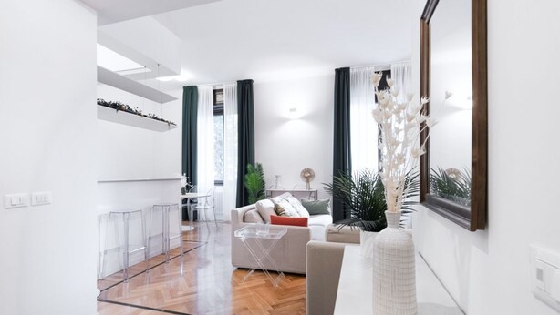 A modern living room with a sofa, coffee table, and decorative vase. There is a dining area with chairs and a table.