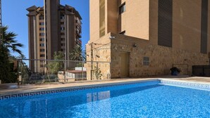 A swimming pool with a tiled edge, surrounded by a building with a stone facade and a door. - FLORIDA sea view apartment (Benidorm)