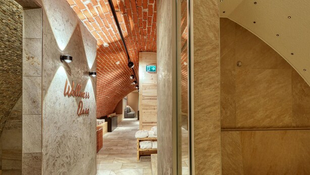 Un pasillo con techo de ladrillo, un cartel que dice "Wellness Oasis" y un banco de madera.