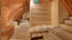 Un cuarto de spa con un arco de ladrillo, paredes de madera, un banco de madera y un pequeño armario de madera.