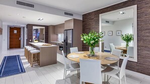 Een moderne keuken met een centraal eiland, witte stoelen en een eettafel met een bloevas.