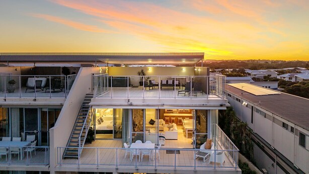 A modern multi-story house with a balcony, a staircase, and a dining area.