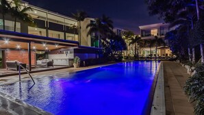 A modern hotel with a swimming pool, outdoor seating, and lush landscaping.