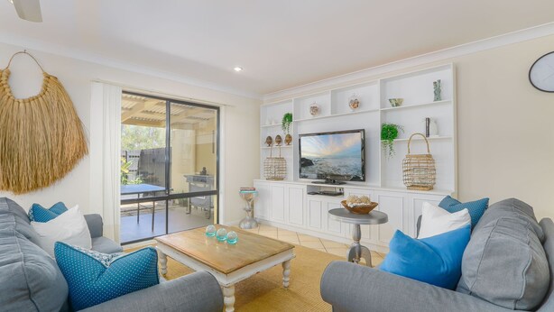 A modern living room with a TV, white cabinets, and a dining area.