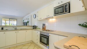 A modern kitchen with white cabinets, a microwave, a stove, and a sink.