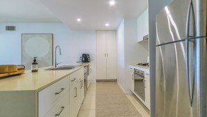 A modern kitchen with a stainless steel refrigerator, a built-in oven, and a sink. - Drift Pool View 21 - Elegant Apartment with Spectacular Lagoon Pool and Tropical Garden Views (Casuarina)
