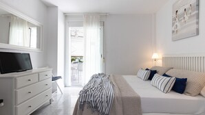 Un dormitorio con una cama, televisor, cómoda y un cuadro en la pared.