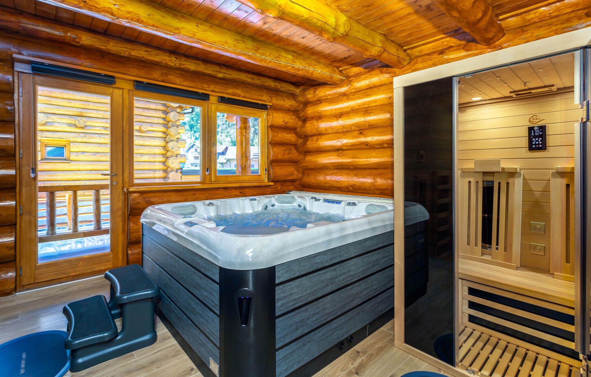 Een chaletinterieur met een jacuzzi, houten vloeren en een sauna.