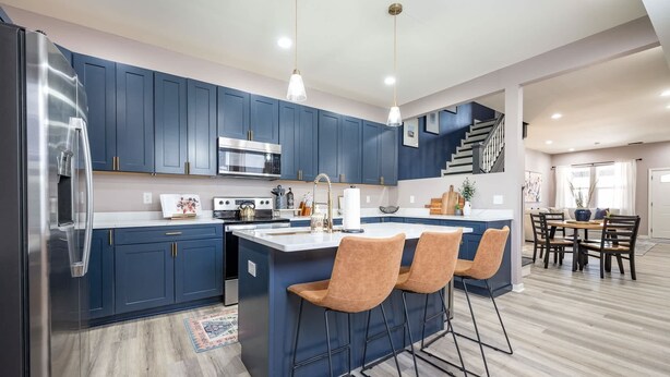 A modern kitchen with dark blue cabinets, stainless steel appliances, and a central island with bar stools. - Indy Elegance | Minutes to Downtown | Free Parking (Indianapolis)