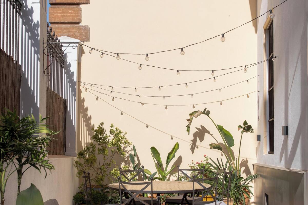 An outdoor patio area with string lights, wicker furniture, and potted plants.