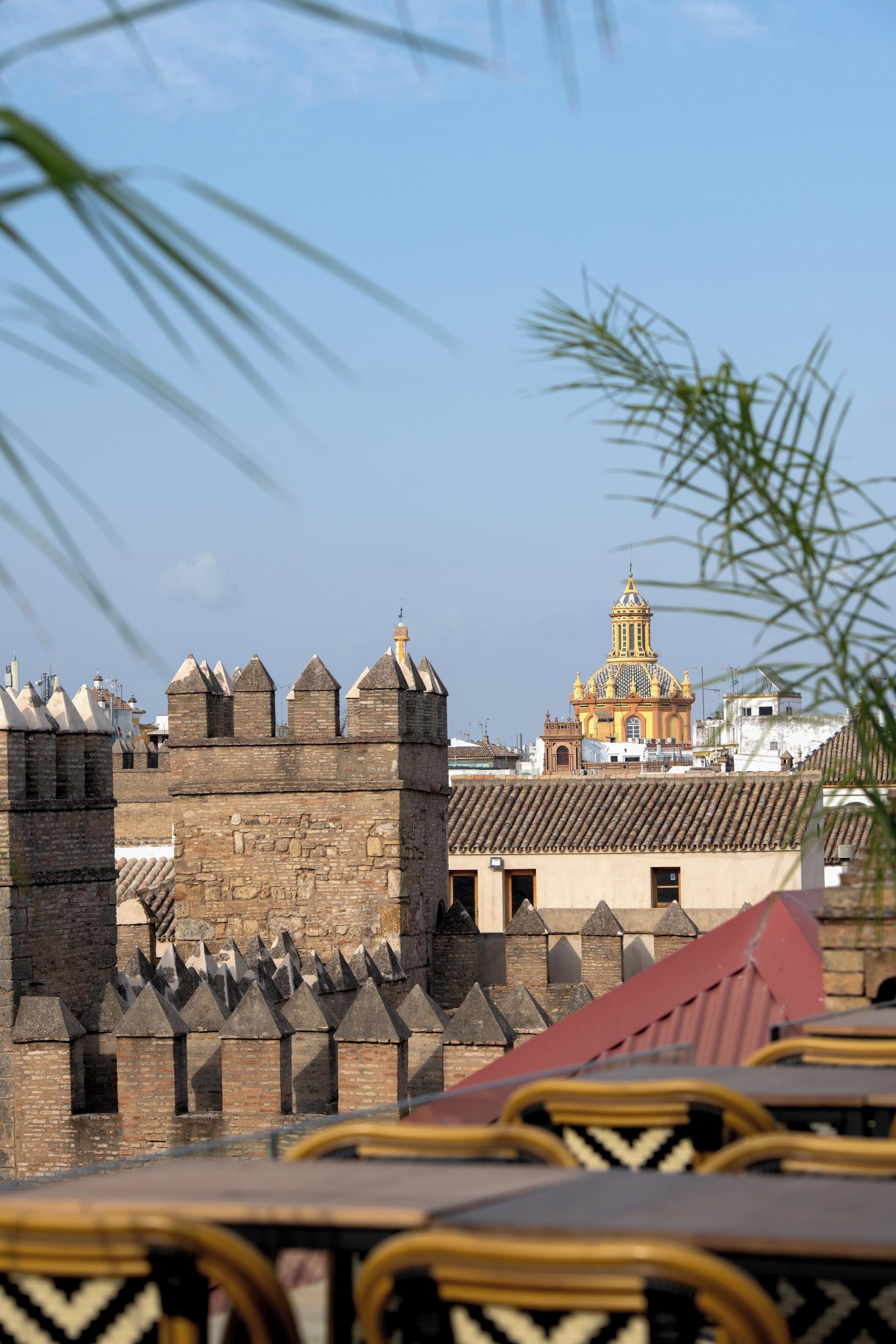 Uma fortaleza histórica com uma torre imponente e um edifício de cúpula amarela ao fundo.