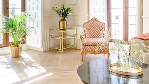 A spacious room with a round marble table, a gold-framed chair, and a hanging light fixture. - Casa del Contratador by Época Suites (Seville)