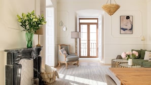 Una habitación bien iluminada con chimenea, una silla de madera, un sofá y una mesa de comedor.