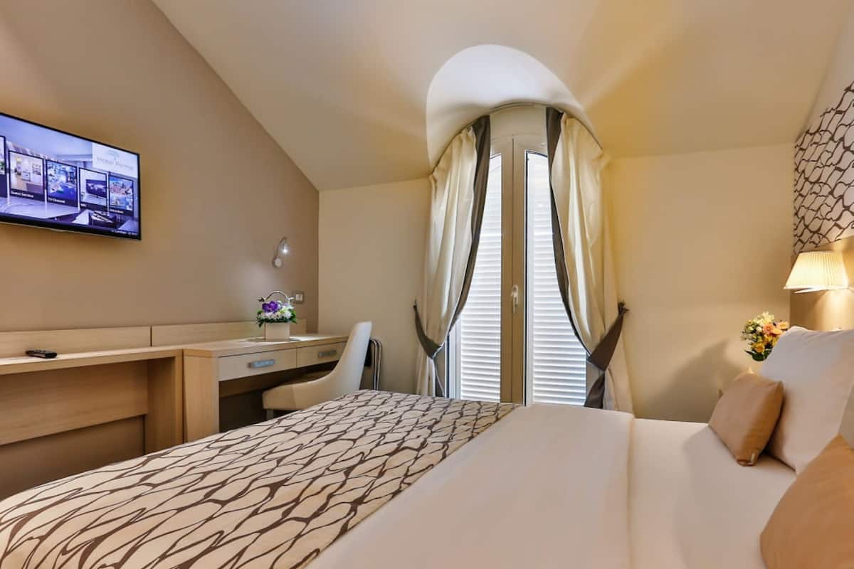 A hotel room with a bed, desk, and TV.