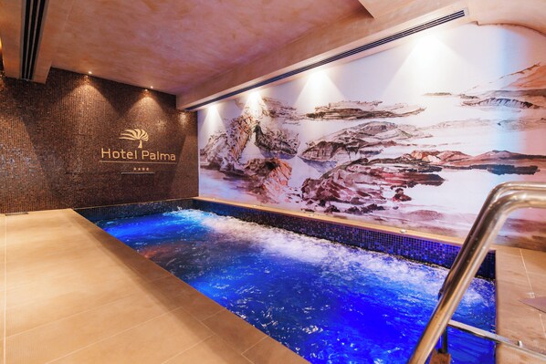 Uma área de piscina de hotel com um mural, uma placa indicando Hotel Palma e uma escada para entrar na piscina.