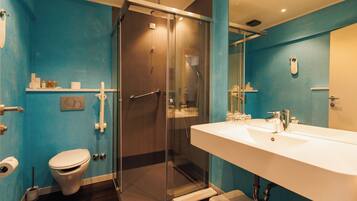 A bathroom with a glass-enclosed shower, a white sink, and a toilet.
