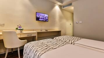 A hotel room with a bed, a desk, and a TV mounted on the wall.