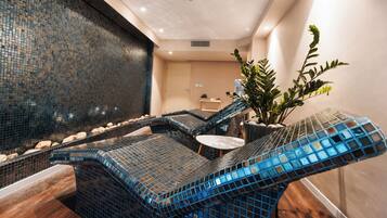 Un área de spa con un muro de mosaicos, una zona de estar con una fuente de agua y una planta en maceta.