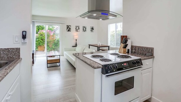 A modern kitchen with a built-in stove, a large window, and a dining area with a table and chairs. - A/C, 3 blocks to beach, dogs, shopping, dining (San Diego)