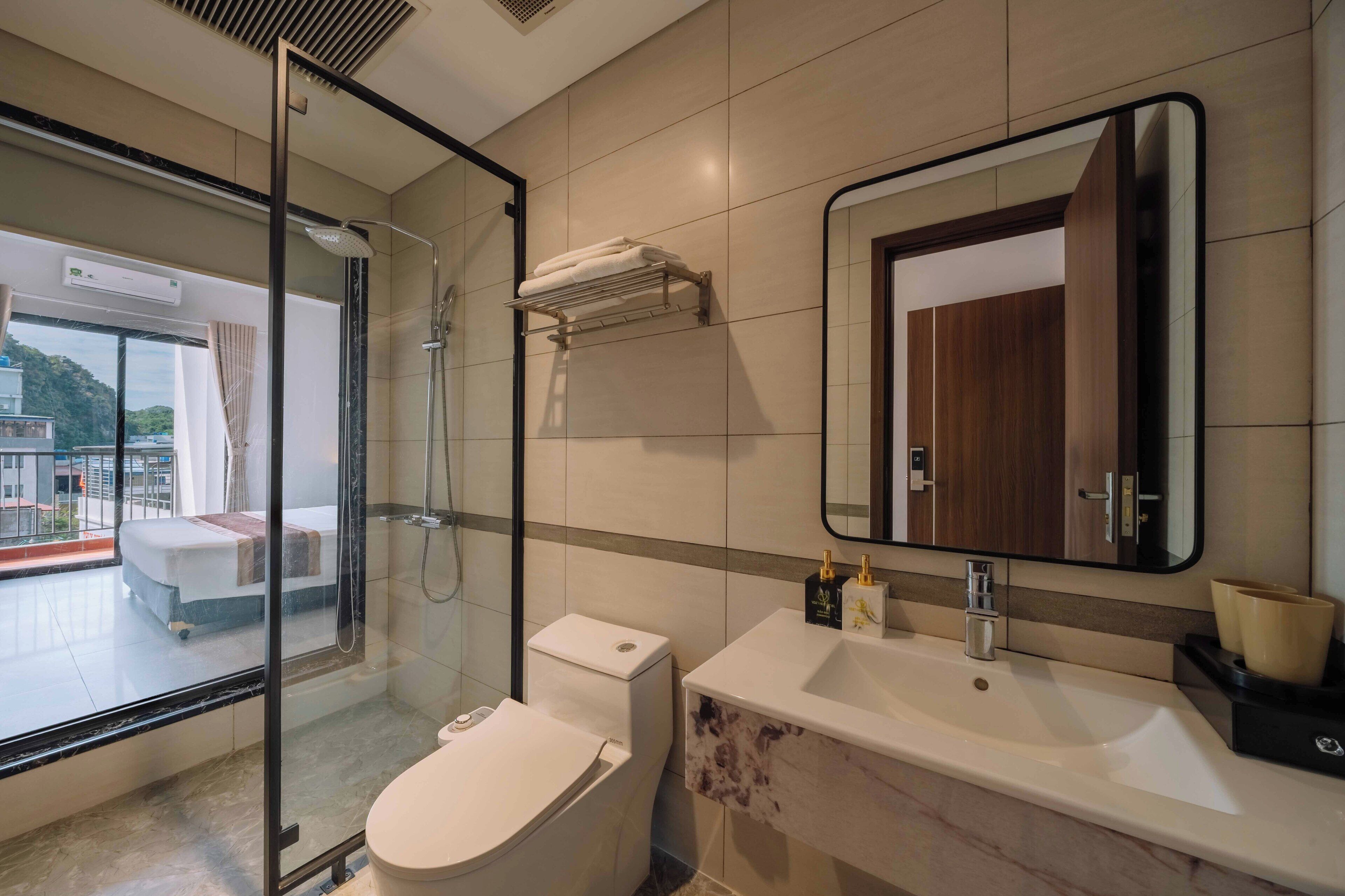 A modern bathroom with a glass-enclosed shower, a toilet, a sink, and a large mirror.