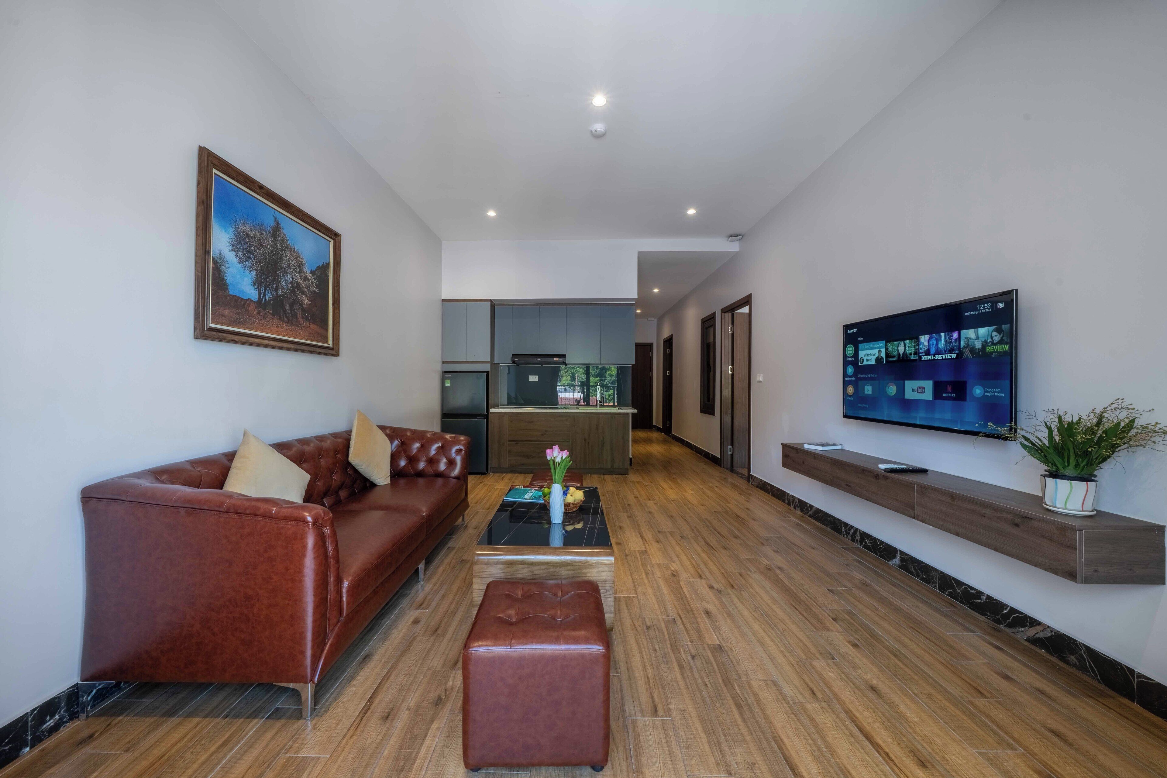Ein modernes Wohnzimmer mit einer Ledersofa, einem Couchtisch und einem an der Wand montierten Fernseher.