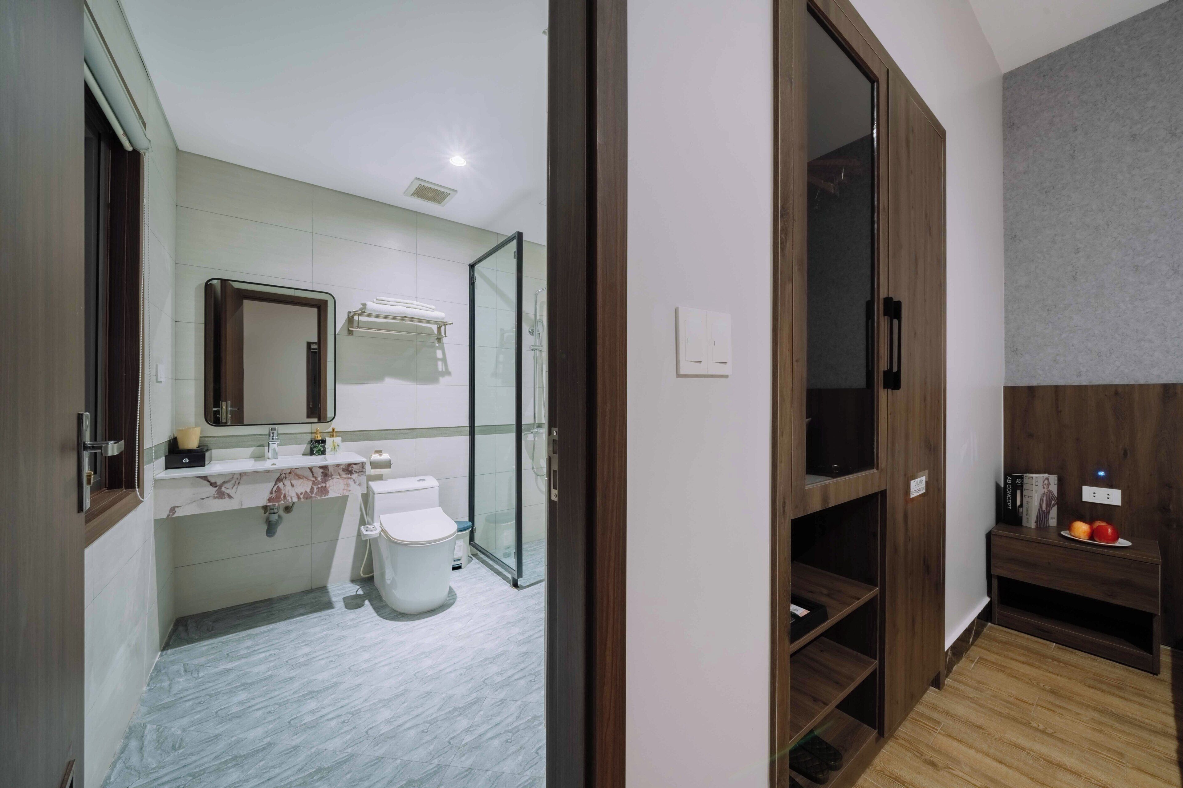 A modern bathroom with a glass shower enclosure, a marble sink, and a toilet.