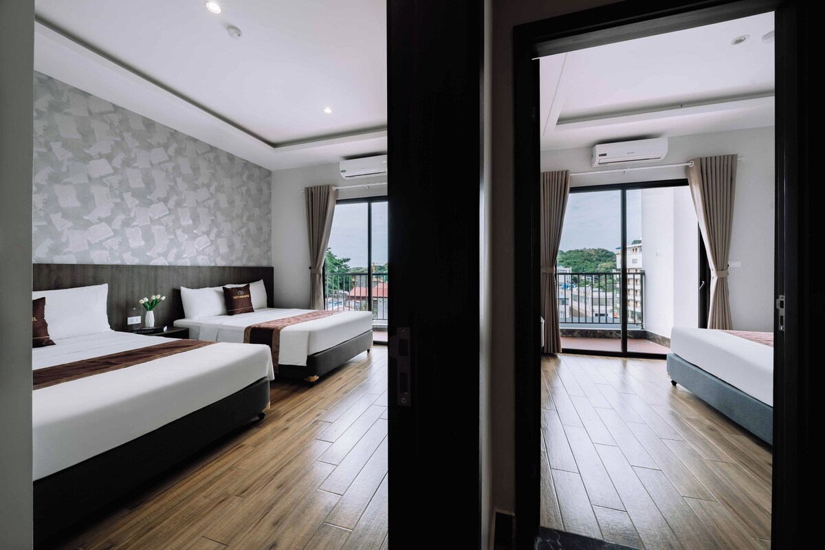 Habitación de hotel con dos camas, un ventanal con vistas y un balcón.