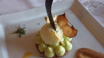 Een dessert op een wit bord met een decoratief element, omringd door kleine blauwe en gele stipjes.