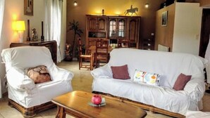 A living room with two white sofas, a wooden coffee table, and a dining area with wooden furniture. - Villa la Patachou à 2 pas du Village de Malaucène (Malaucène)