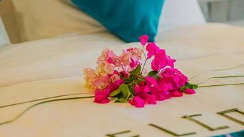 Una cama con almohadones color turquesa, un arreglo floral y la palabra "WELCOME" en la colcha.