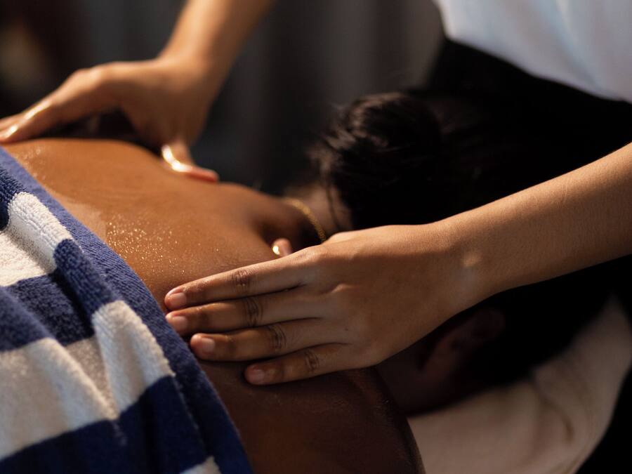 A massage therapy session with a striped towel on the client.