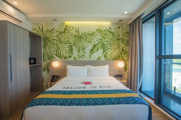 A hotel room with a bed, a wall-mounted phone, a window with curtains, and a tropical leaf wallpaper. - Beach Heaven Guraidhoo by Beach Hotel Maldives (Guraidhoo)
