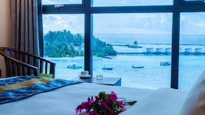 Une chambre d’hôtel dotée d’une grande fenêtre donnant sur la mer et les bateaux.