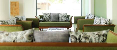 A seating area with green upholstered sofas and armchairs, arranged in a semi-circle.