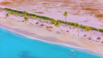 Perto da praia, areia branca, espreguiçadeiras, toalhas de praia 