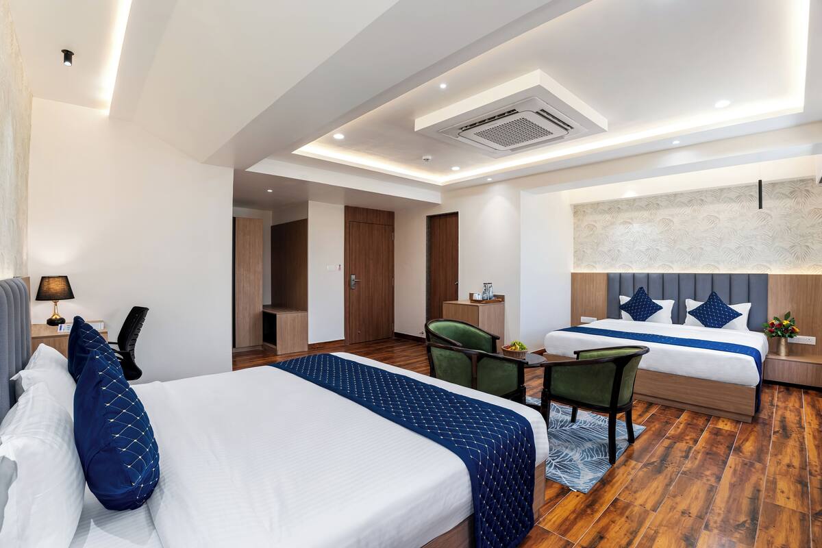 A hotel room with a large bed, a desk, a chair, and a separate seating area with a sofa.