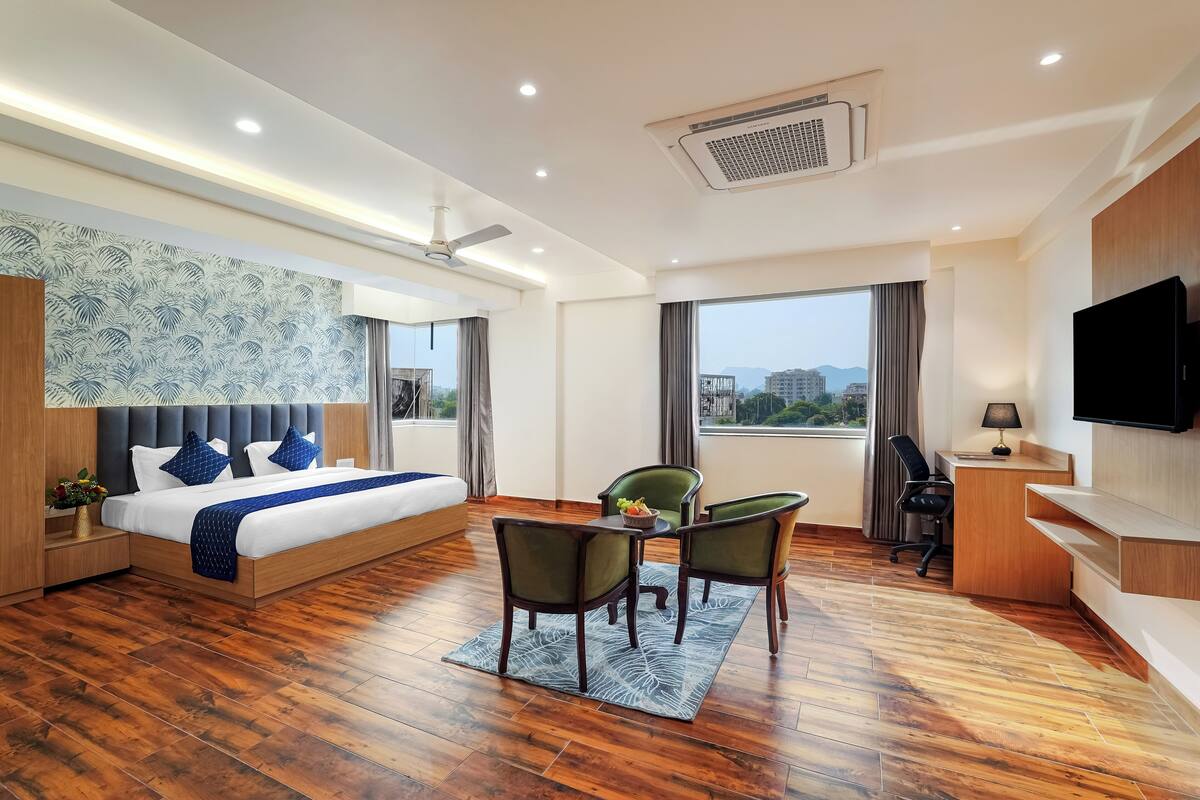 A modern hotel room with a large bed, a desk, and a TV.