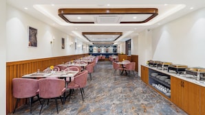 Ein geräumiges Restaurant mit Marmorboden, rosafarbenen Stühlen und einem Buffetbereich.