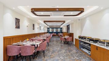 A spacious restaurant with marble flooring, pink chairs, and a buffet area.
