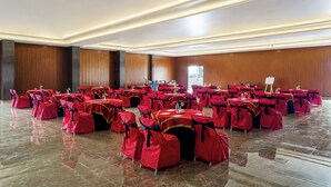 A large hall with rows of tables and chairs, each set covered with red tablecloths and matching chair covers. - VEGA by The Ozone Hotel Udaipur (Udaipur)