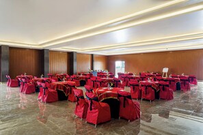 A large hall with rows of tables and chairs, each set covered with red tablecloths and matching chair covers. - VEGA by The Ozone Hotel Udaipur (Udaipur)