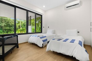 A bedroom with two beds, a window, and an air conditioning unit.